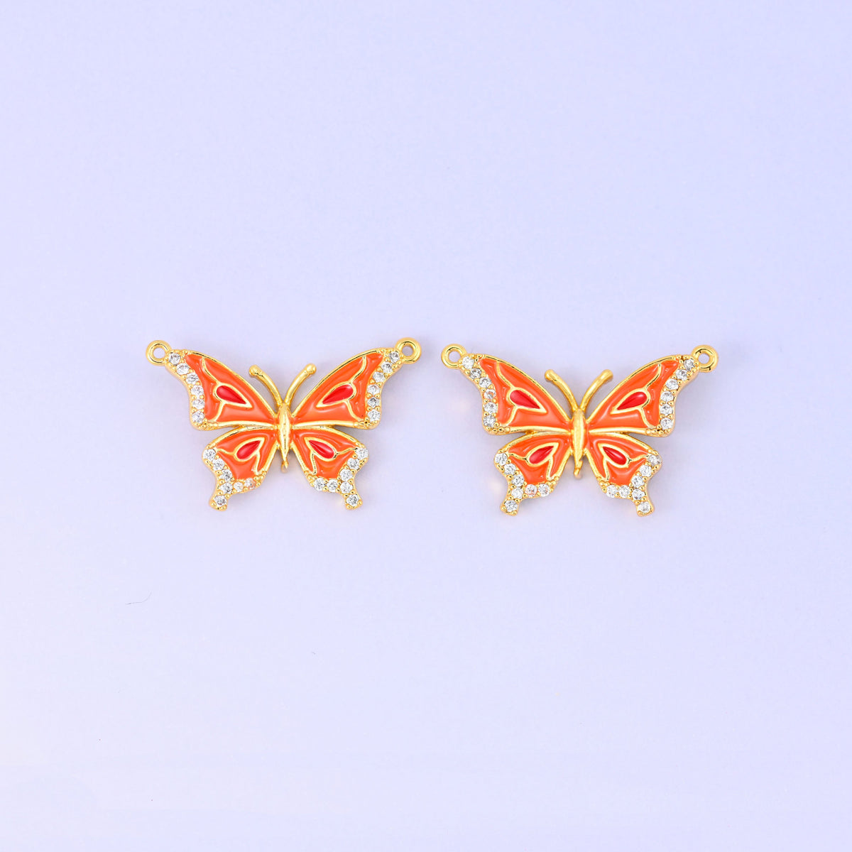 Orange colourway of the enamel butterfly double connector pendant, two gold plated butterflies with orange and red wing markings and zircon set wing edges.