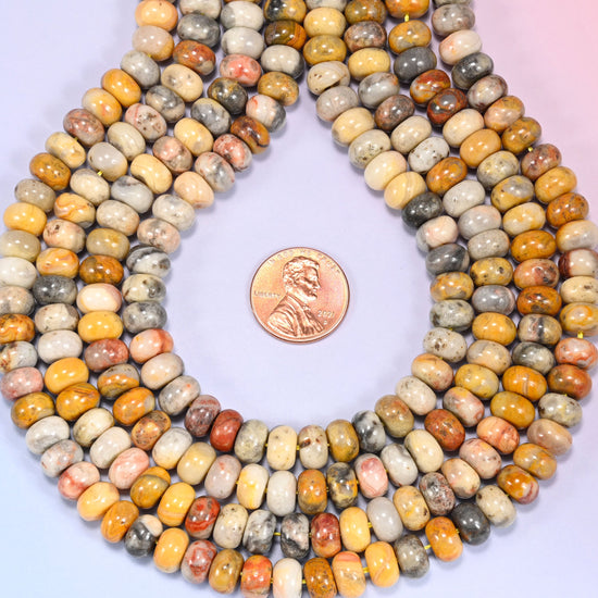 Bundled coil of Crazy Agate rondelle beads on a lavender background with a penny placed at the center for scale.