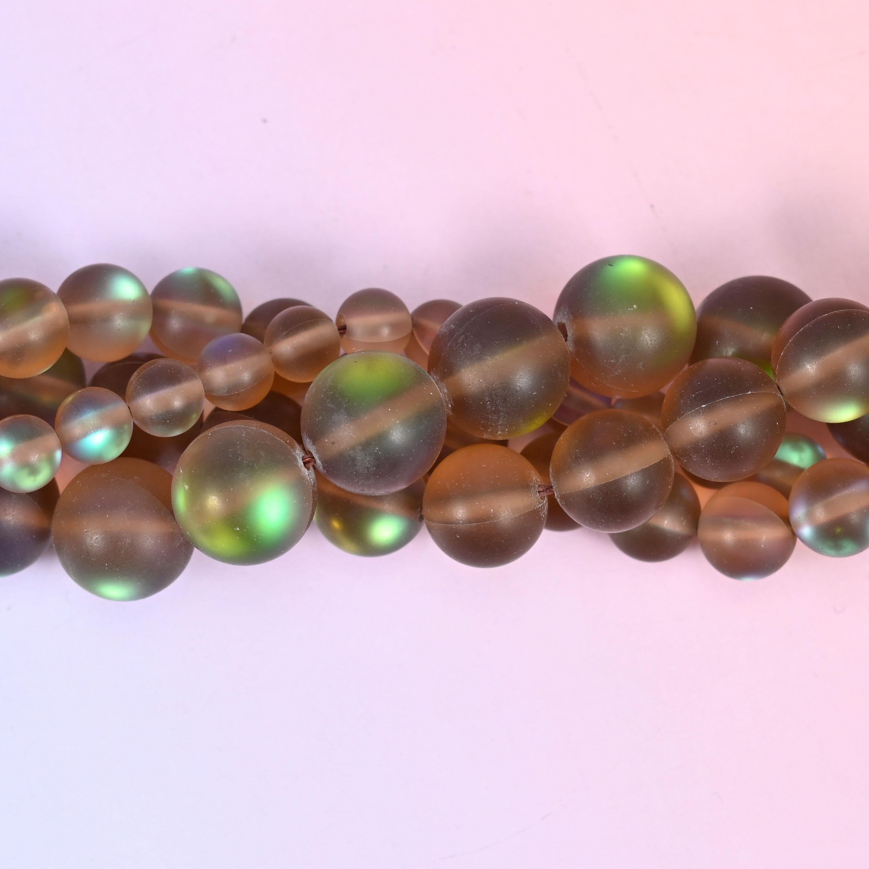 Warm coffee-brown rounds with a soft frosted matte surface, lit from beneath by a shifting green and teal iridescent coating