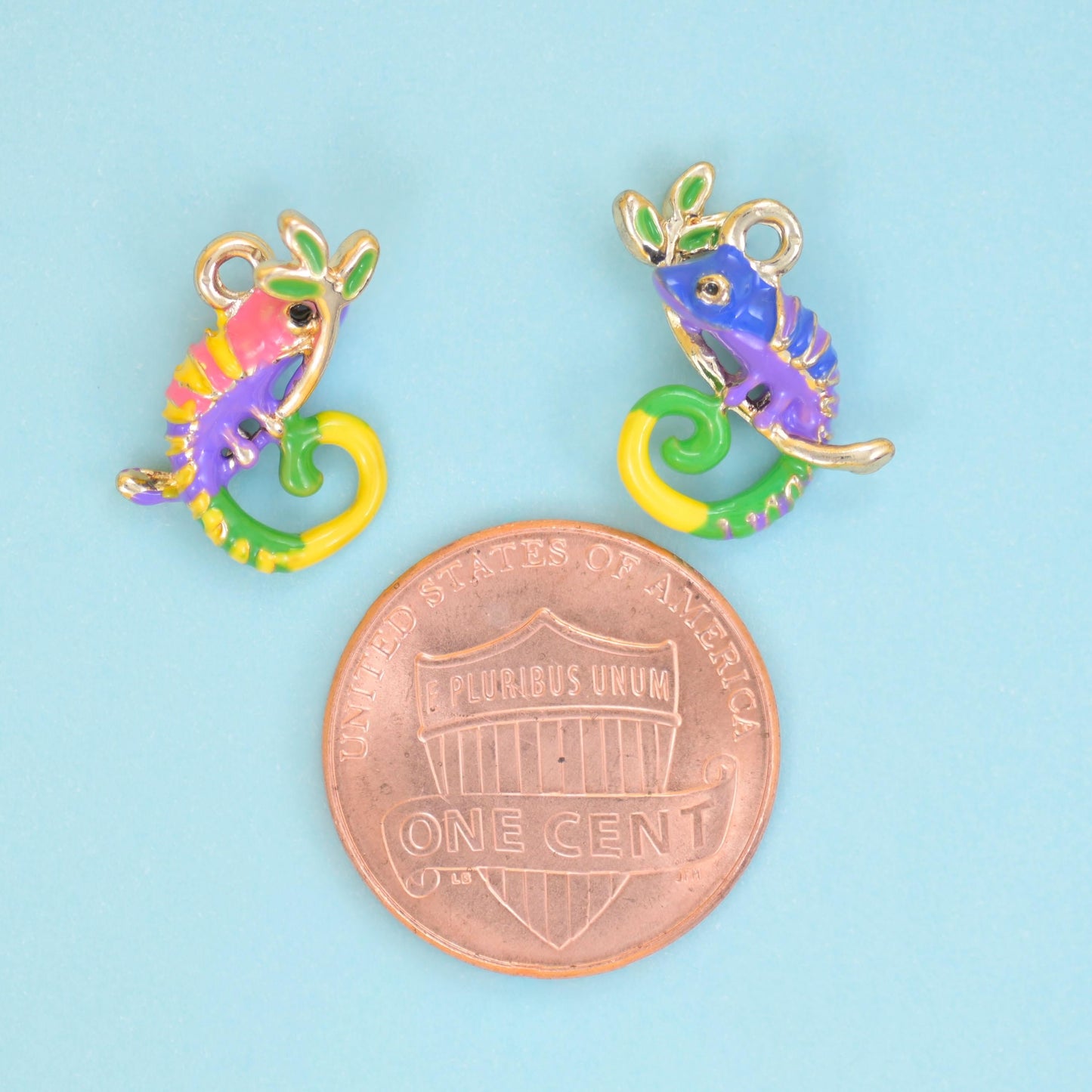 A little chameleon with its tail curled into a spiral, painted in violet, coral pink, lime green and sunny yellow enamel…
