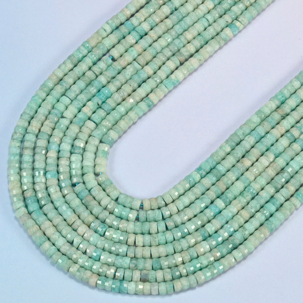 Green amazonite faceted heishi disc beads in several strands curved into a wide U, soft light green stone with beige patches
