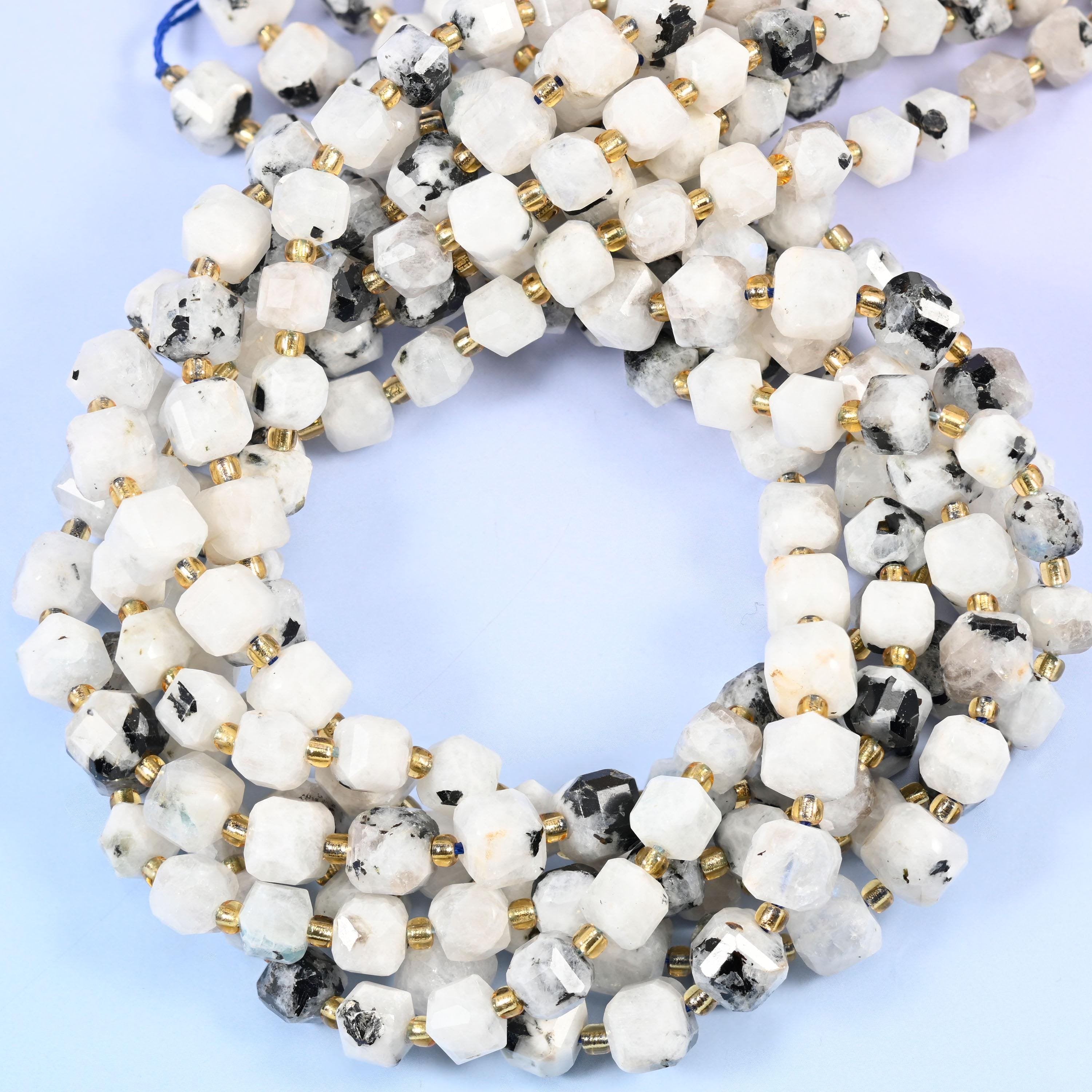 Milky white cubes blotched and flecked with charcoal black, corners cut into facets so light breaks across the flat faces. Despite the Blue Moonstone name these read white and grey in hand, not blue.