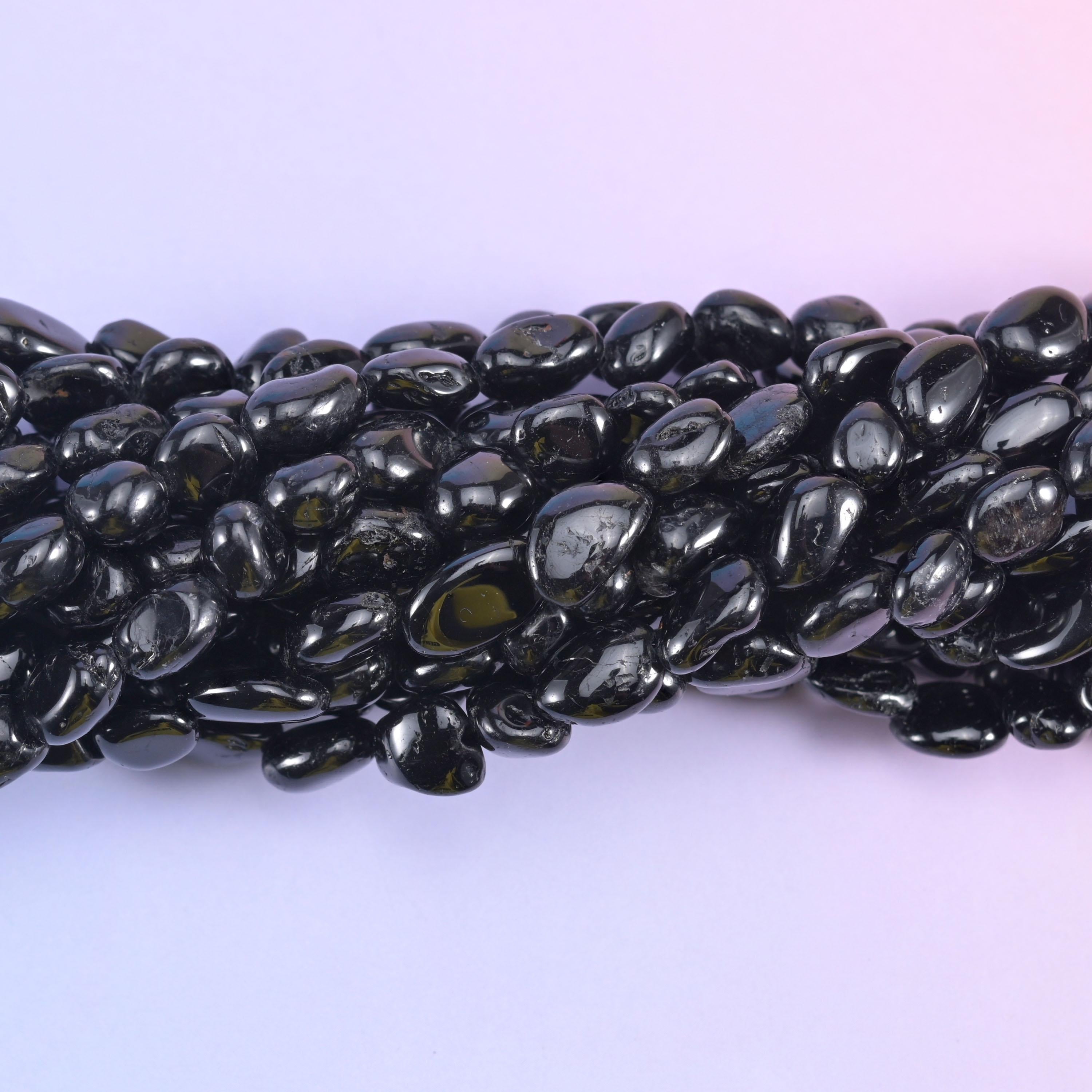Close macro of polished black tourmaline pebbles with high-gloss highlights