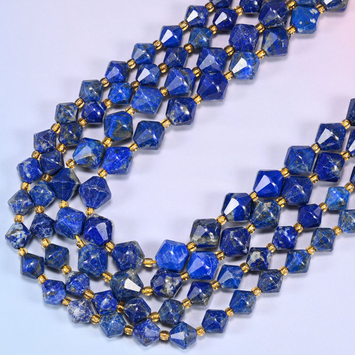 Lapis lazuli bicone beads in a wide loop curving down and back, the blue running from mid to very deep across the strand.