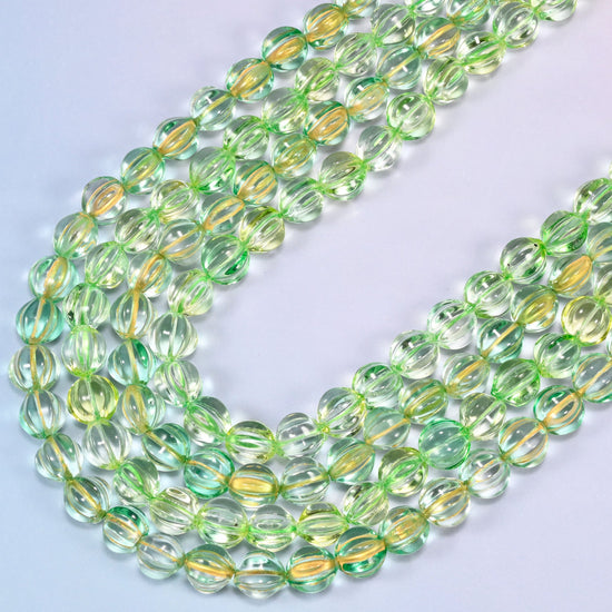Green gold pumpkin glass beads, several strands laid in a wide sweeping curve across the frame.