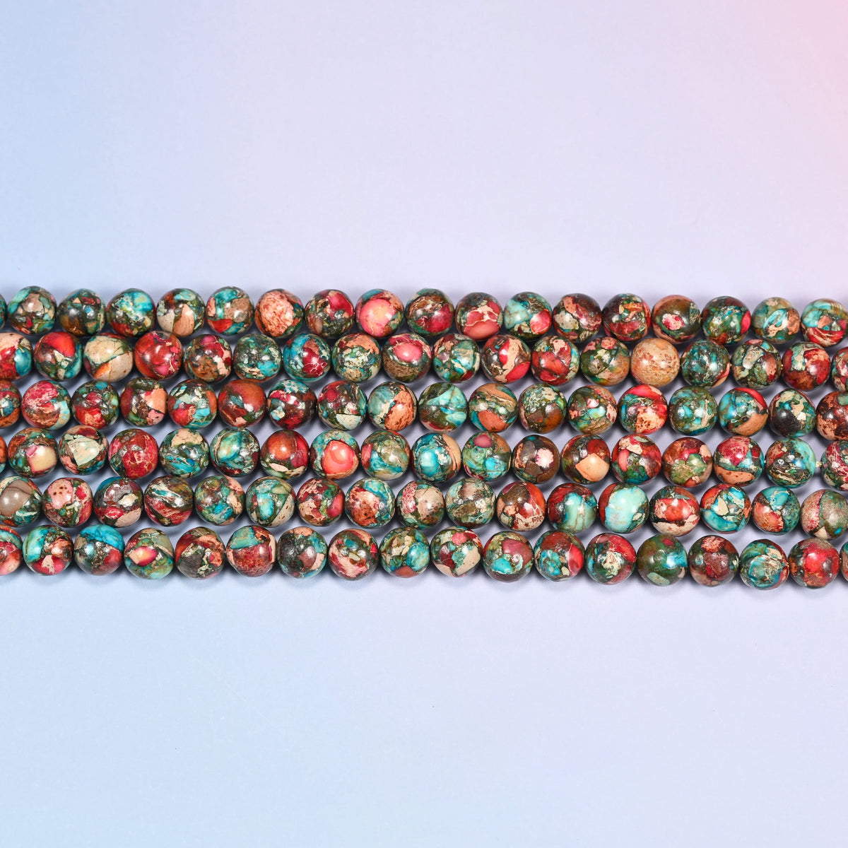 Close-up of red sea sediment jasper smooth round beads in four horizontal rows, red and turquoise marbling across every bead.