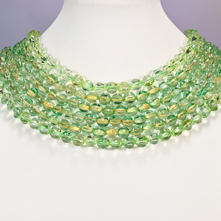 Green gold pumpkin glass beads shown as layered strands on a white neck display form.
