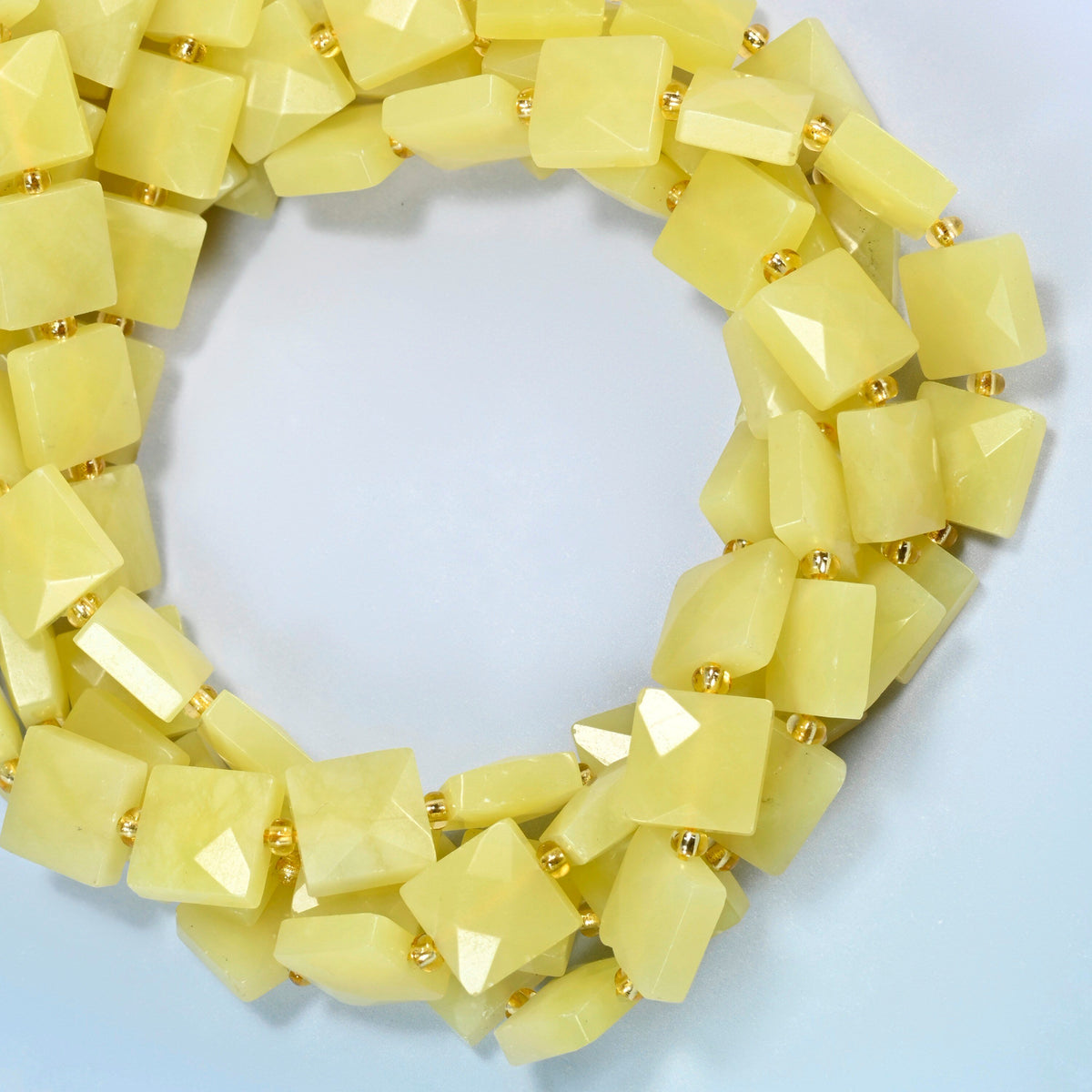 Lemon Jade faceted flat square beads coiled into overlapping loops, whole strands of soft lemon yellow stone