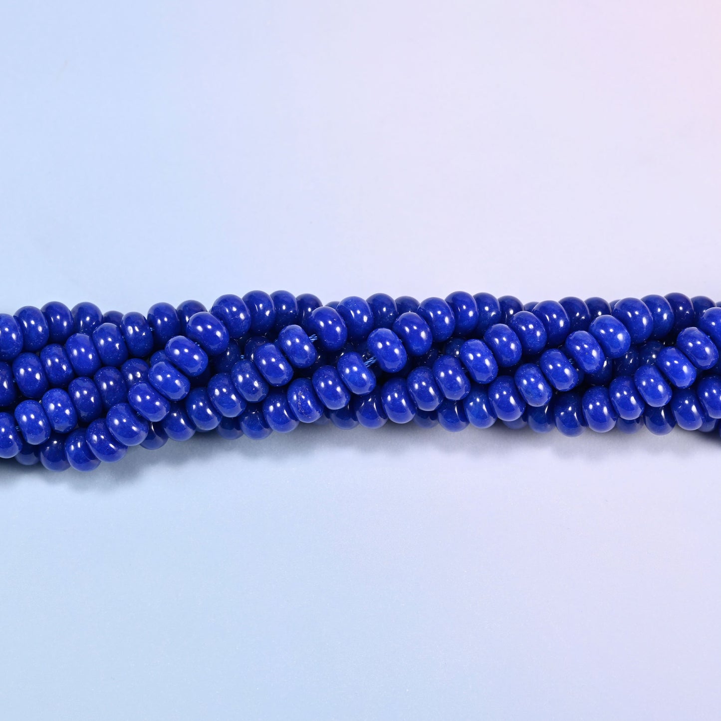 Twisted strands of Dark Blue dyed jade gemstone rondelle beads, showing how the discs stack into a ribbed line