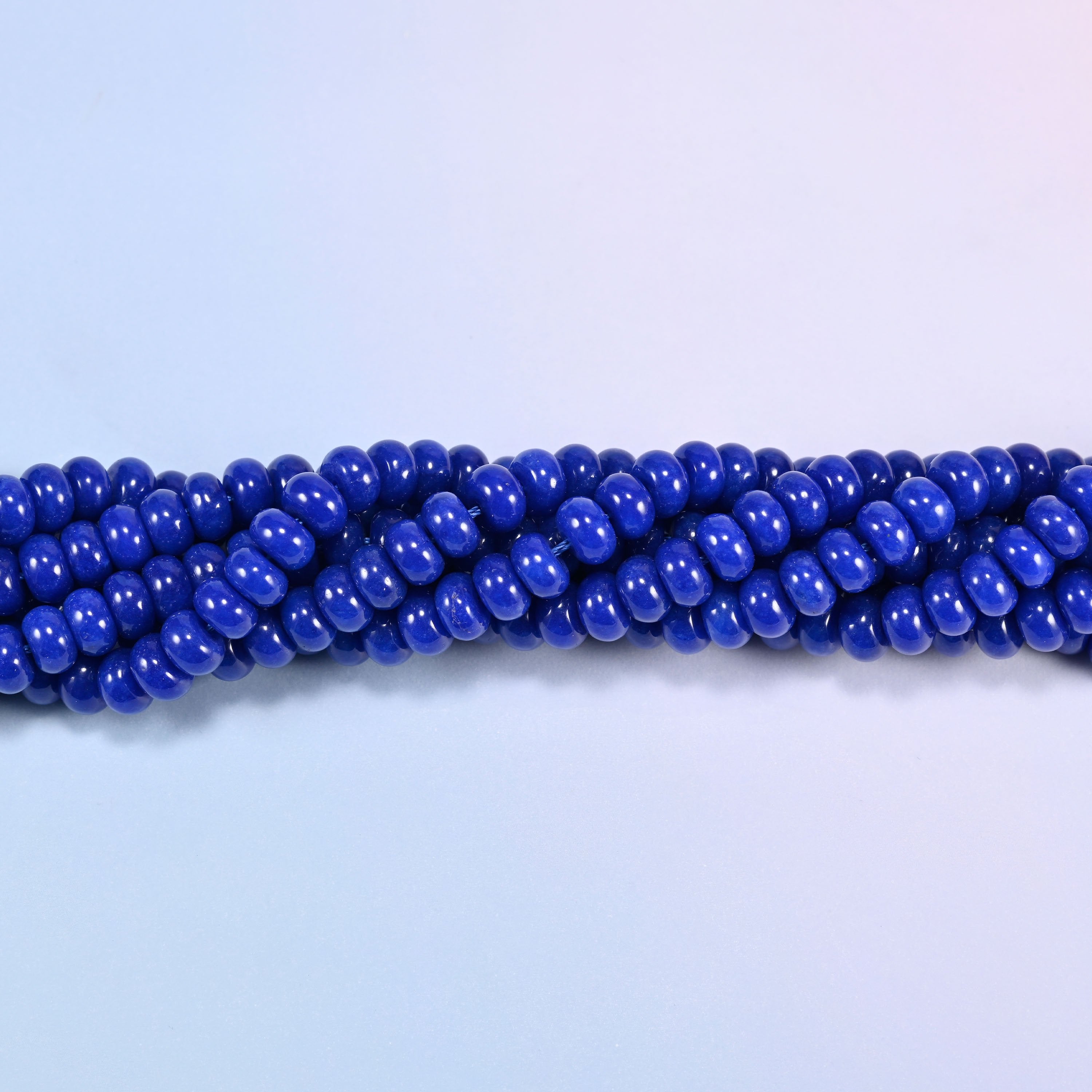 Twisted strands of Dark Blue dyed jade gemstone rondelle beads, showing how the discs stack into a ribbed line