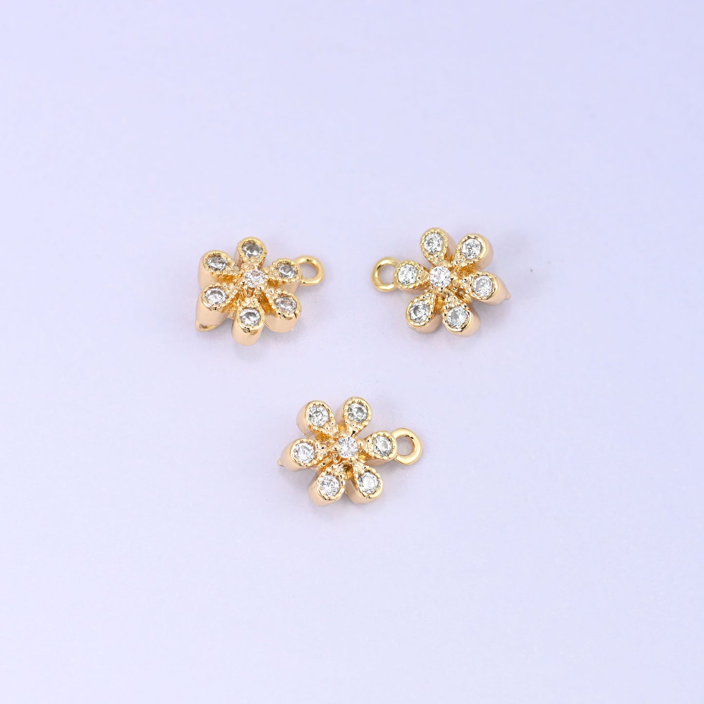 Small gold charms, three flower charms shown close up with the top ring visible