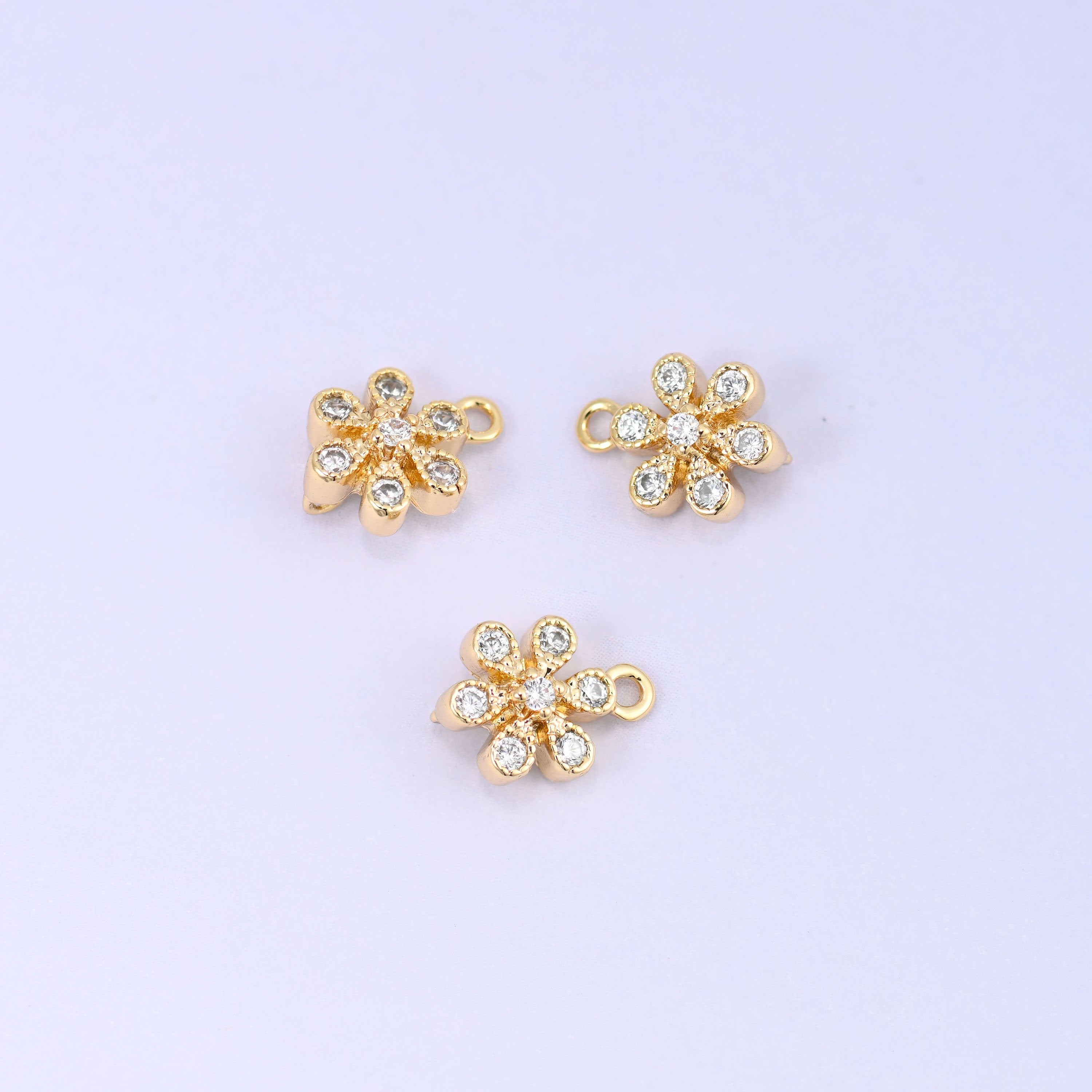 Small gold charms, three flower charms shown close up with the top ring visible