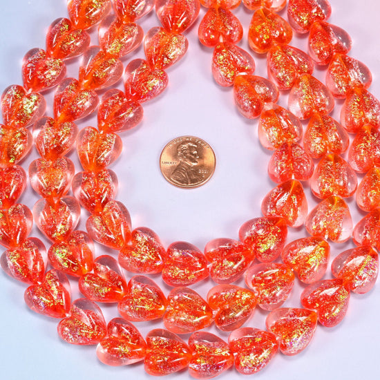 Warm coral-red transparent hearts, thick and glossy, shot through with golden iridescent glitter