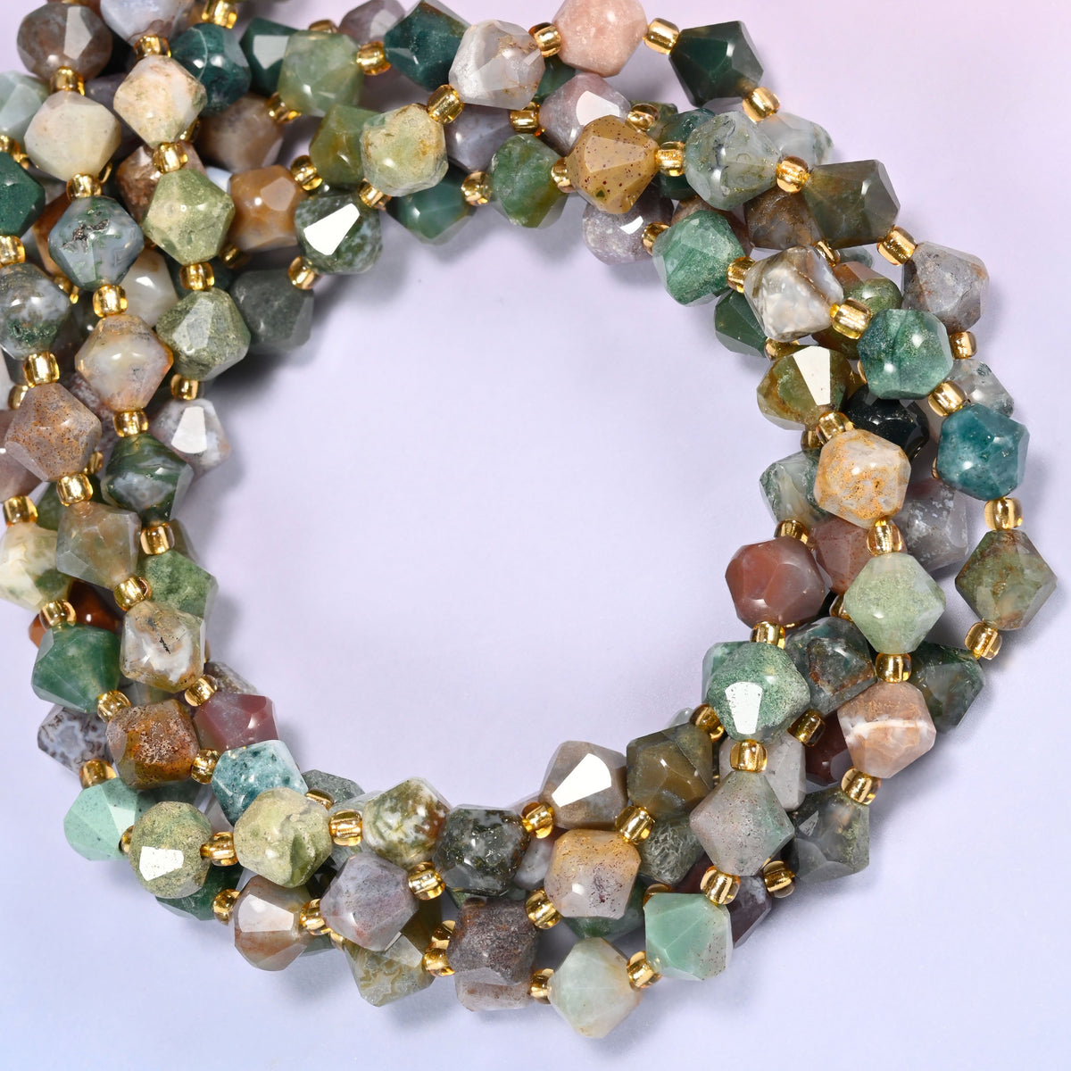 Indian Agate faceted bicone beads 8mm with gold-tone spacers, strand coiled into a tighter circle, close-up view