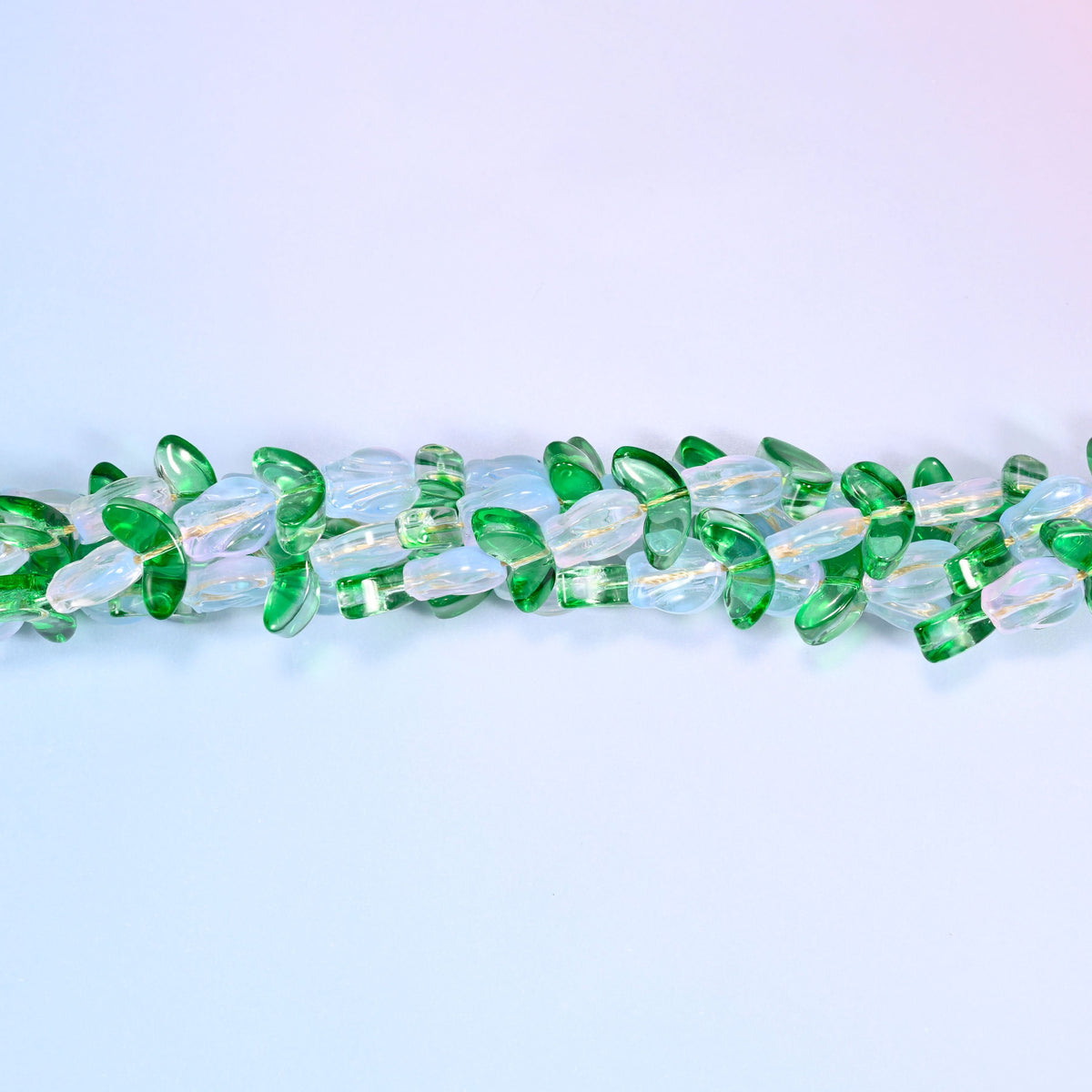 White and opal-toned tulip-shaped glass beads paired with green leaf-shaped glass beads for botanical-inspired jewelry.