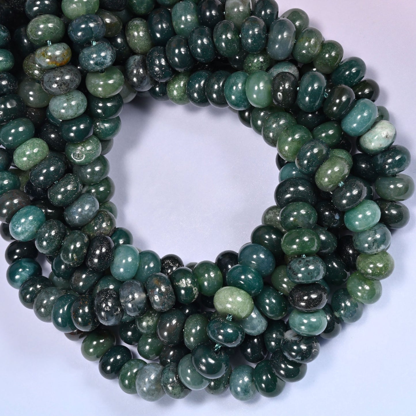 Close-up horizontal row of Moss Agate beads showing the green stone pattern in a tightly coiled strand.