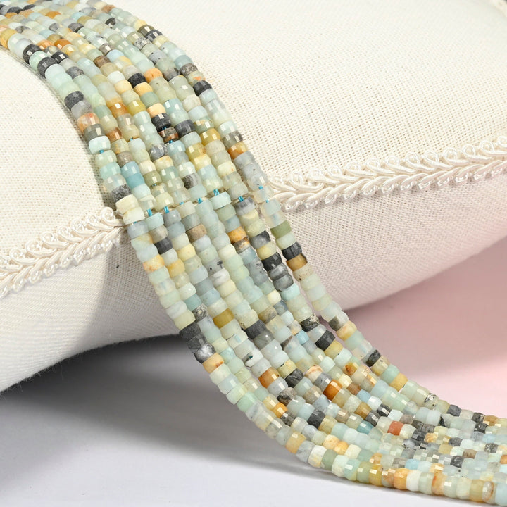 Multi-color amazonite faceted heishi disc beads 2x4mm, several strands draped over a white cushion