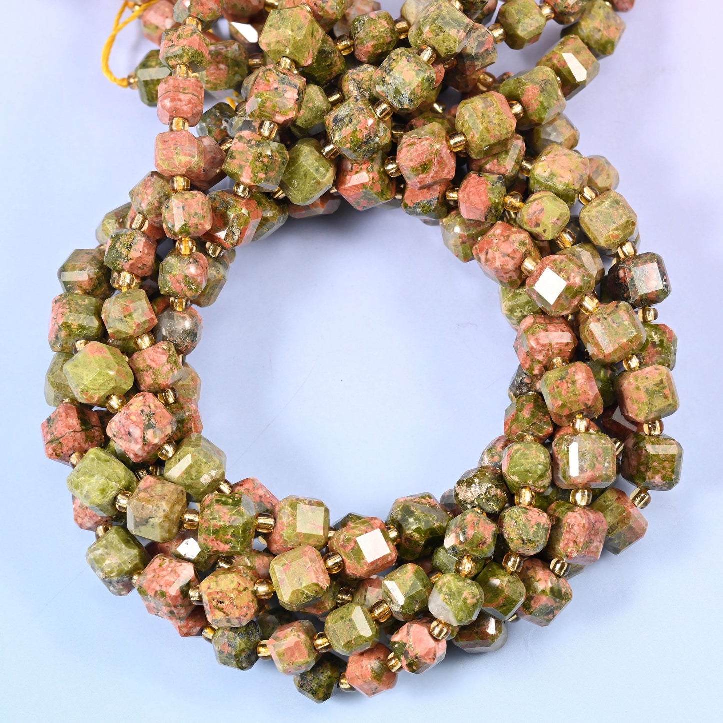 Olive and moss green cubes blotched with salmon pink and cream, every corner cut away so the two colours break across separate small planes.