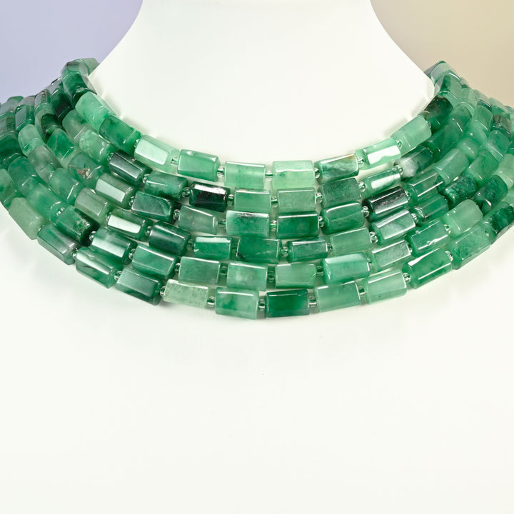 African jade faceted tube strands arranged as a layered collar on a white display bust, emerald and forest green beads across the neck