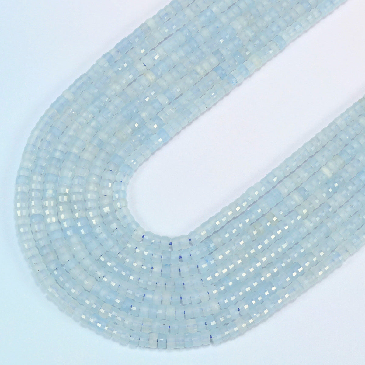 Aquamarine chalcedony faceted heishi disc beads in several strands curved into a wide U, light icy blue translucent stone