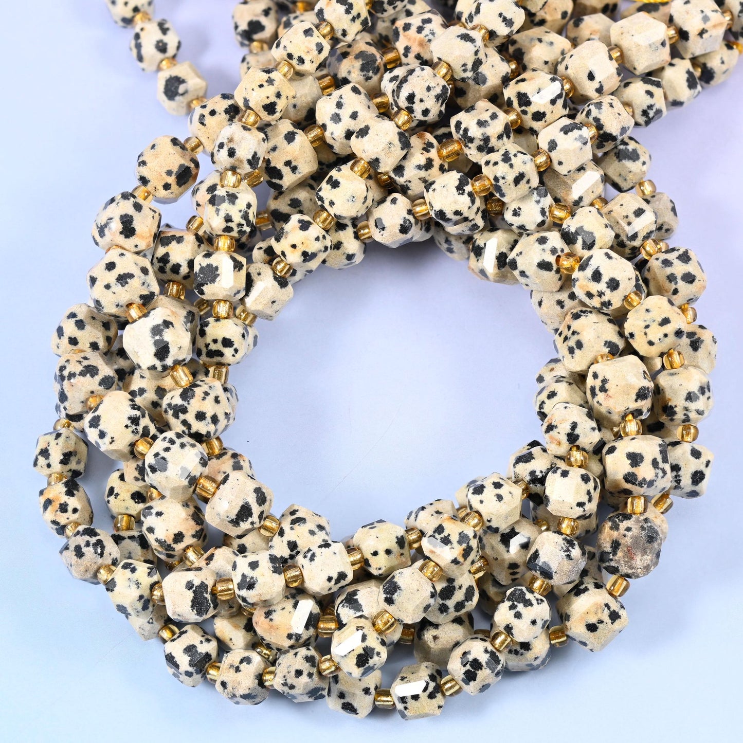 Bone-white and cream cubes spotted with inky black, faceted at the corners so the speckling breaks across several small planes.