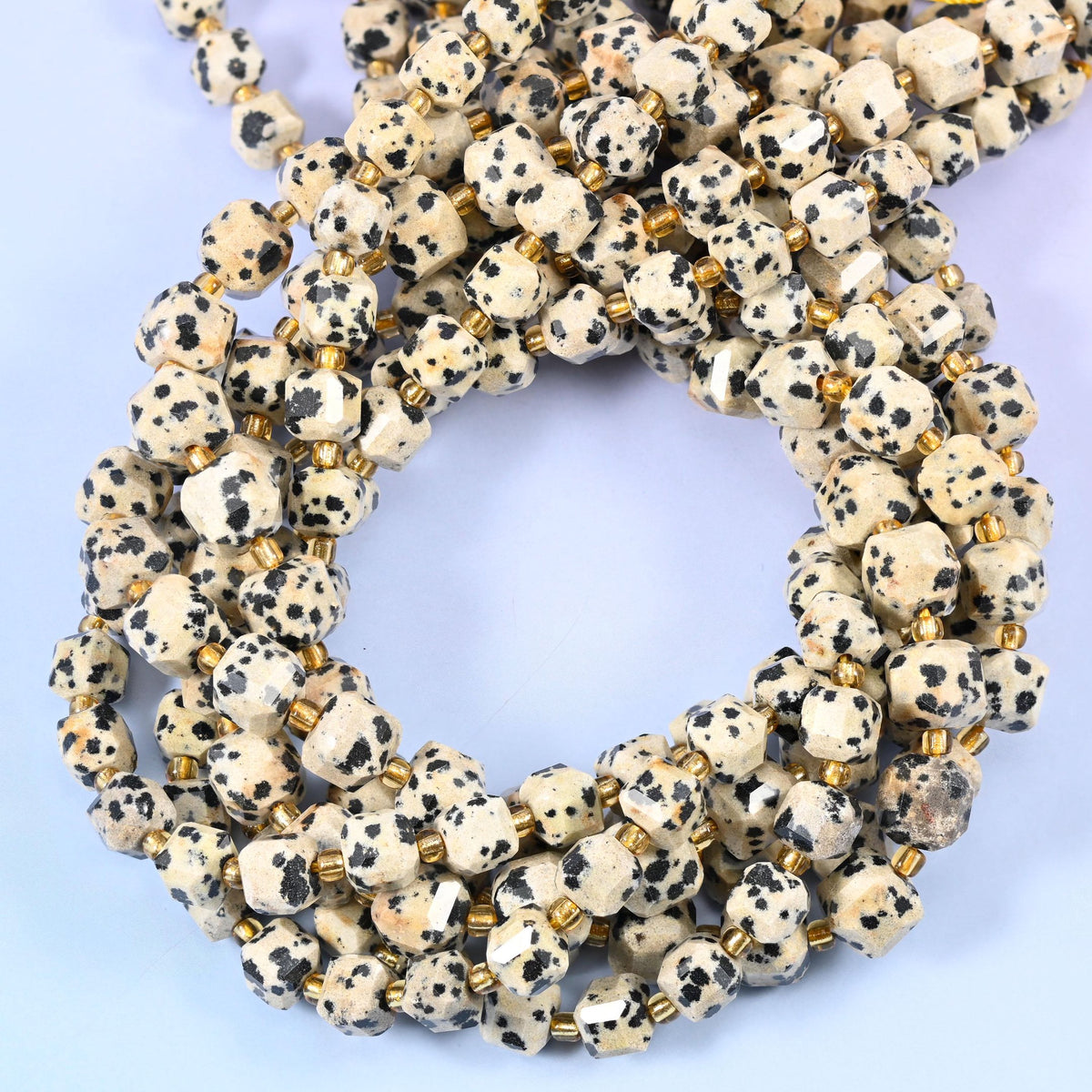 Bone-white and cream cubes spotted with inky black, faceted at the corners so the speckling breaks across several small planes.