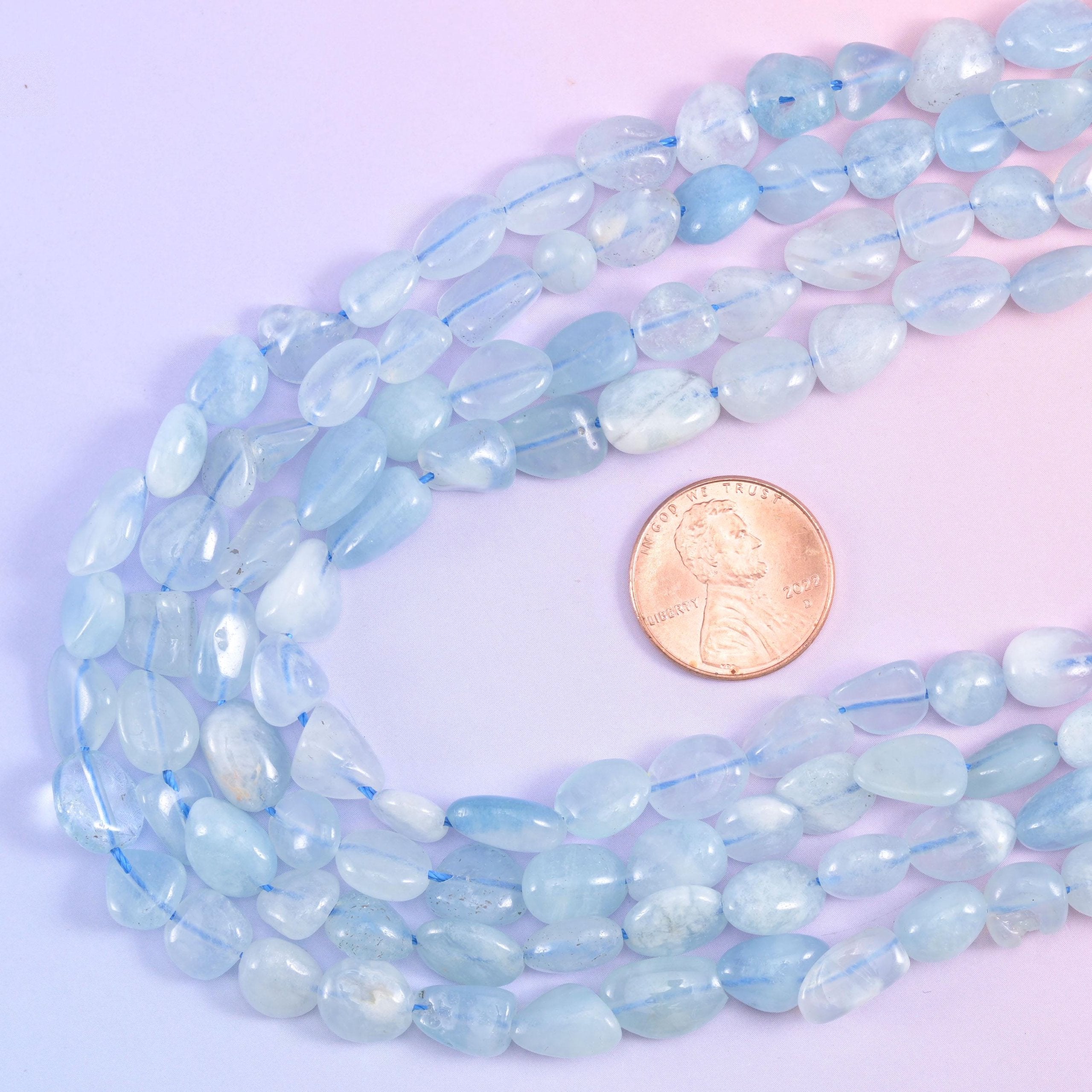 Aquamarine nugget strands looped beside a US penny for size reference