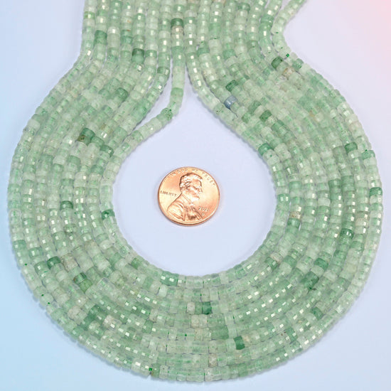 Green strawberry quartz faceted heishi disc strands formed into a teardrop loop around a US penny for scale