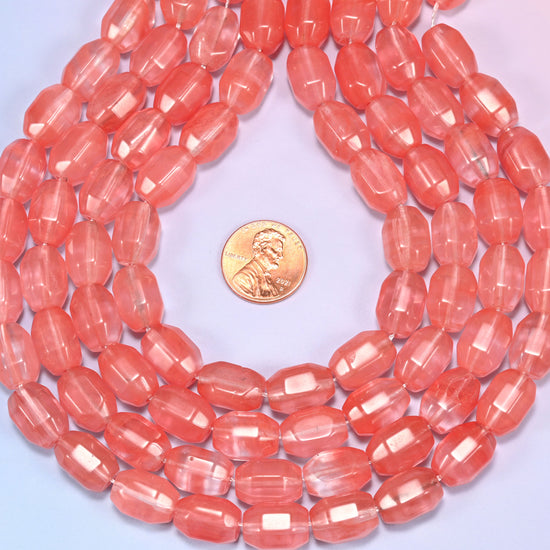 Wide circular coil of faceted glass barrel bead strands on a light background with a penny in the center for size comparison.