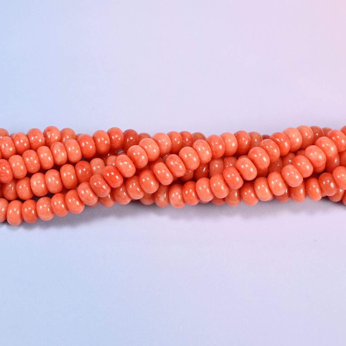 Twisted strands of Red Orange dyed jade gemstone rondelle beads, showing how the discs stack into a ribbed line