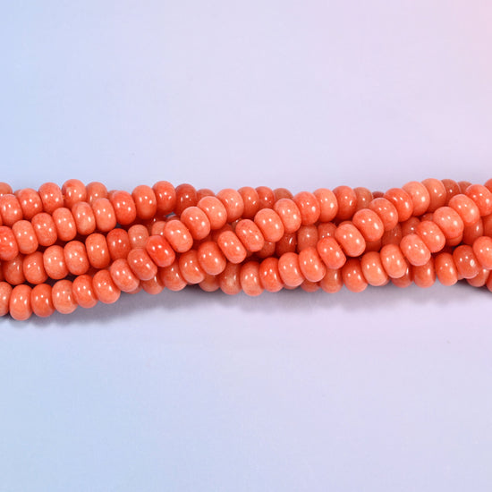 Twisted strands of Red Orange dyed jade gemstone rondelle beads, showing how the discs stack into a ribbed line