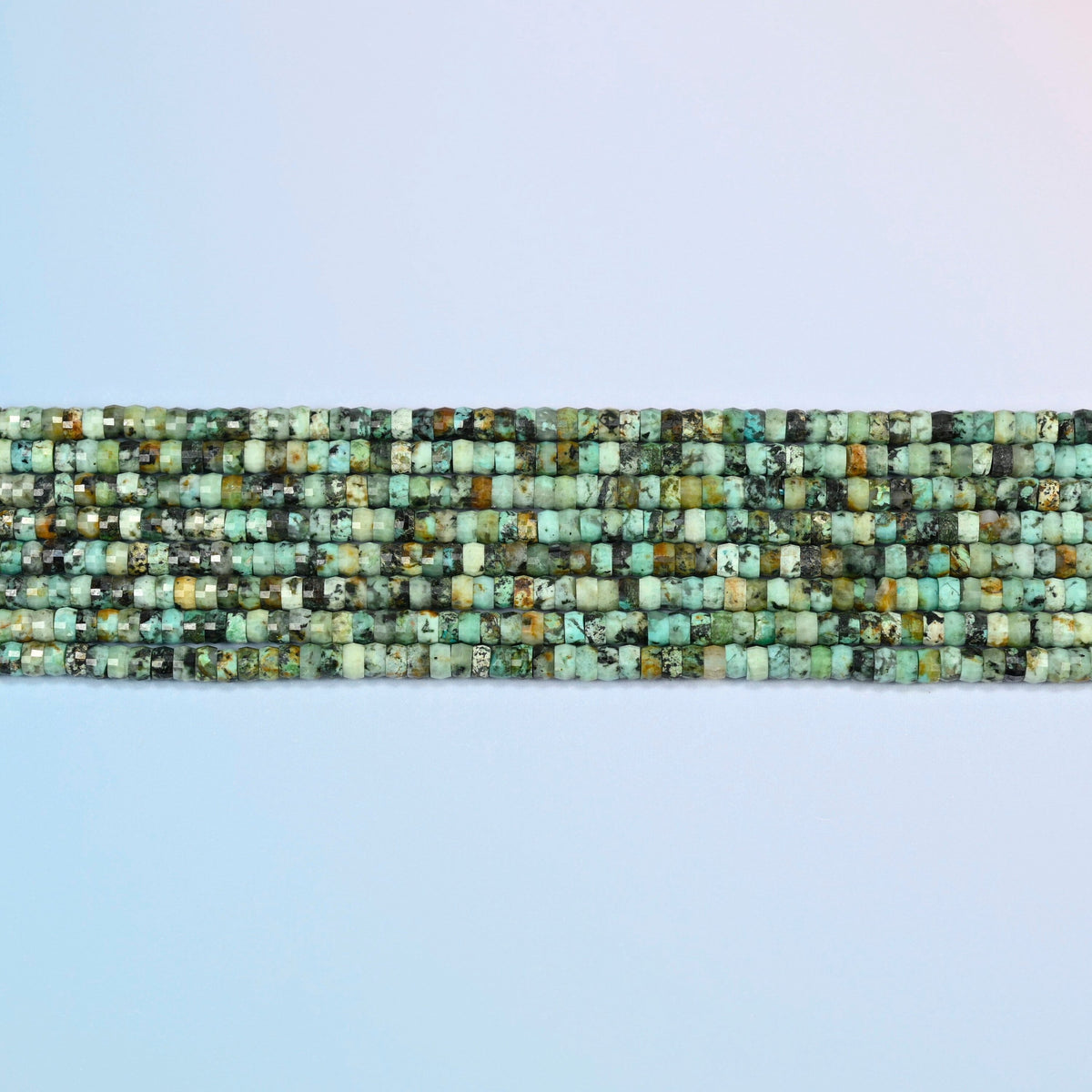 Several strands of African howlite faceted heishi disc beads laid in straight rows