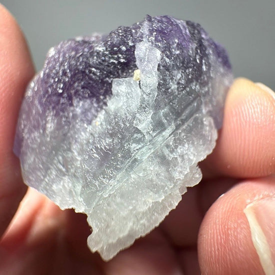 Angled view of the fluorite piece showing the sugary crystalline surface across the purple zone