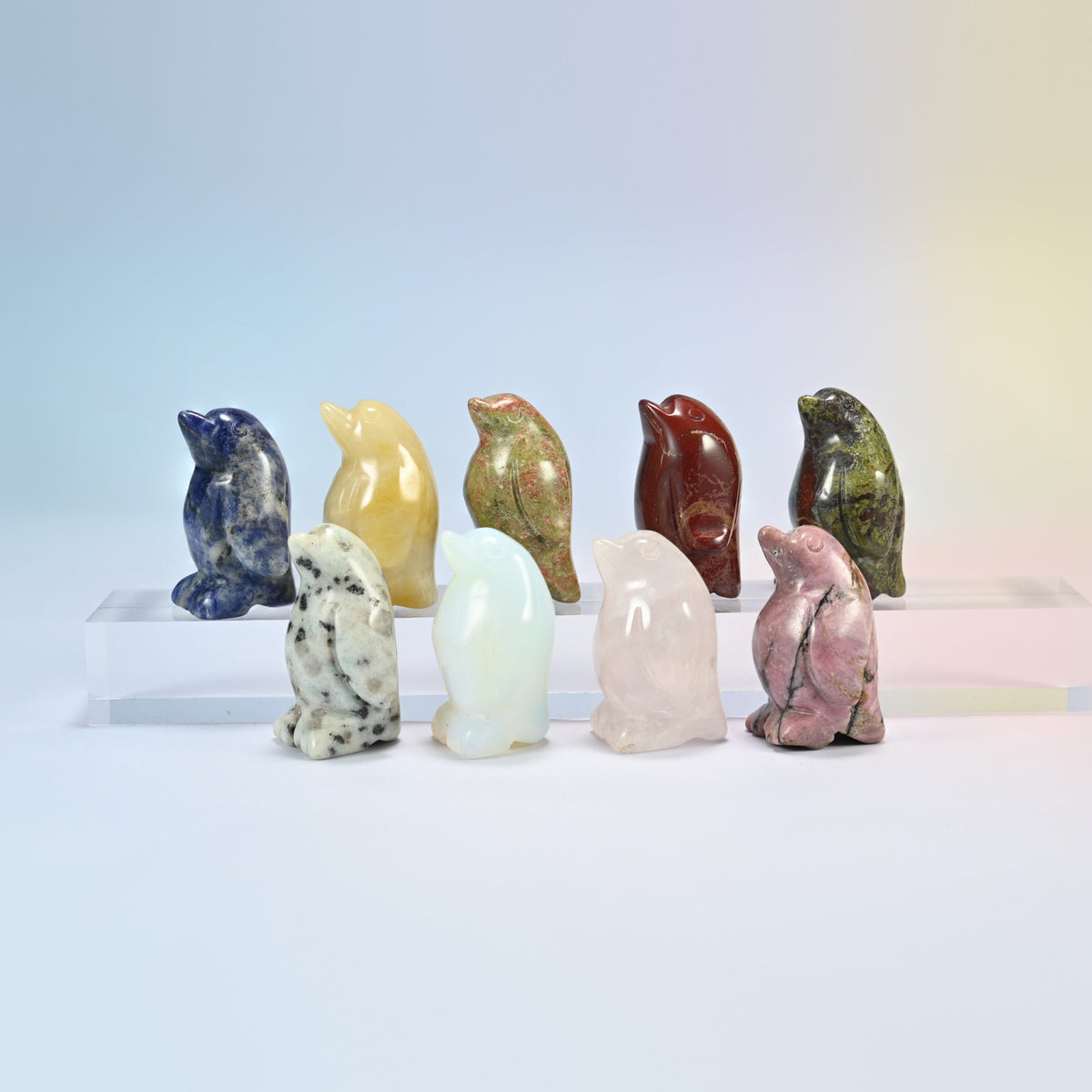 Group of 1.5 inch penguin crystal carvings in natural sodalite, yellow jade, unakite, red jasper, kiwi jasper, rose quartz, rhodonite and opalite