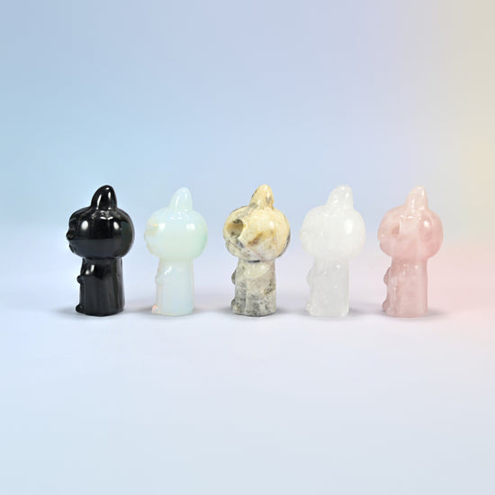 Side view of five pumpkin skull carvings with curled stems: black obsidian, opalite, crazy agate, clear quartz and rose quartz