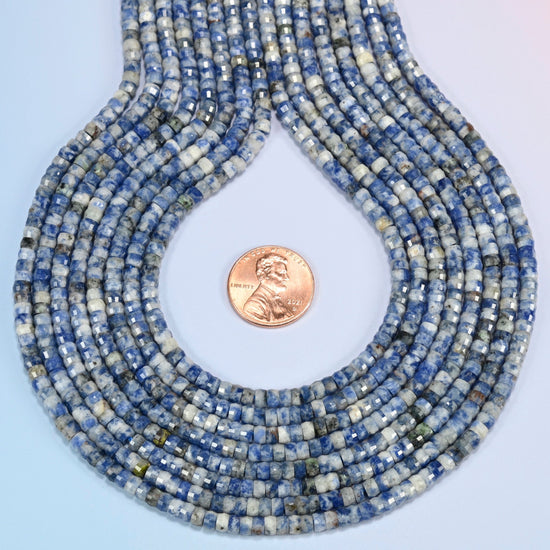 Blue spot jasper faceted heishi disc strands formed into a teardrop loop around a US penny for scale
