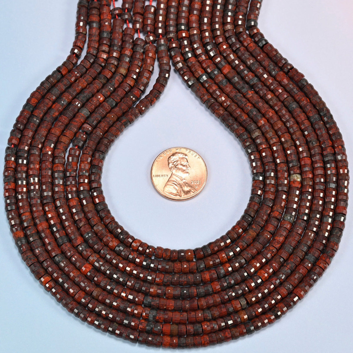 Zhanguo red agate faceted heishi disc strands formed into a teardrop loop around a US penny for scale