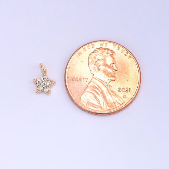 Small gold charms, one star charm shown beside a US penny for size