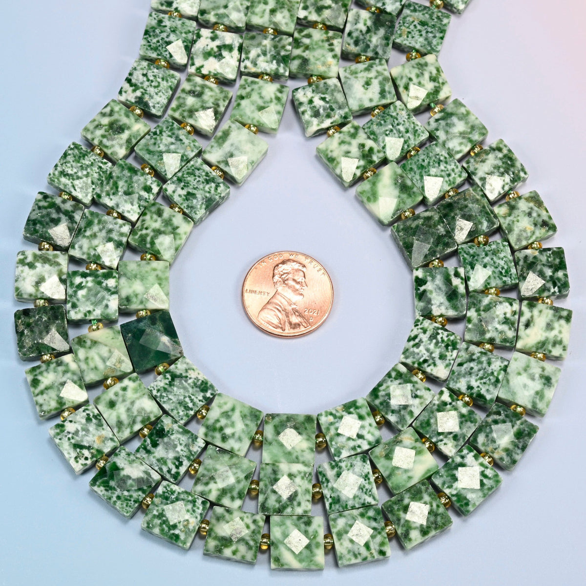 Tree agate faceted flat square strands formed into a teardrop loop around a US penny for scale