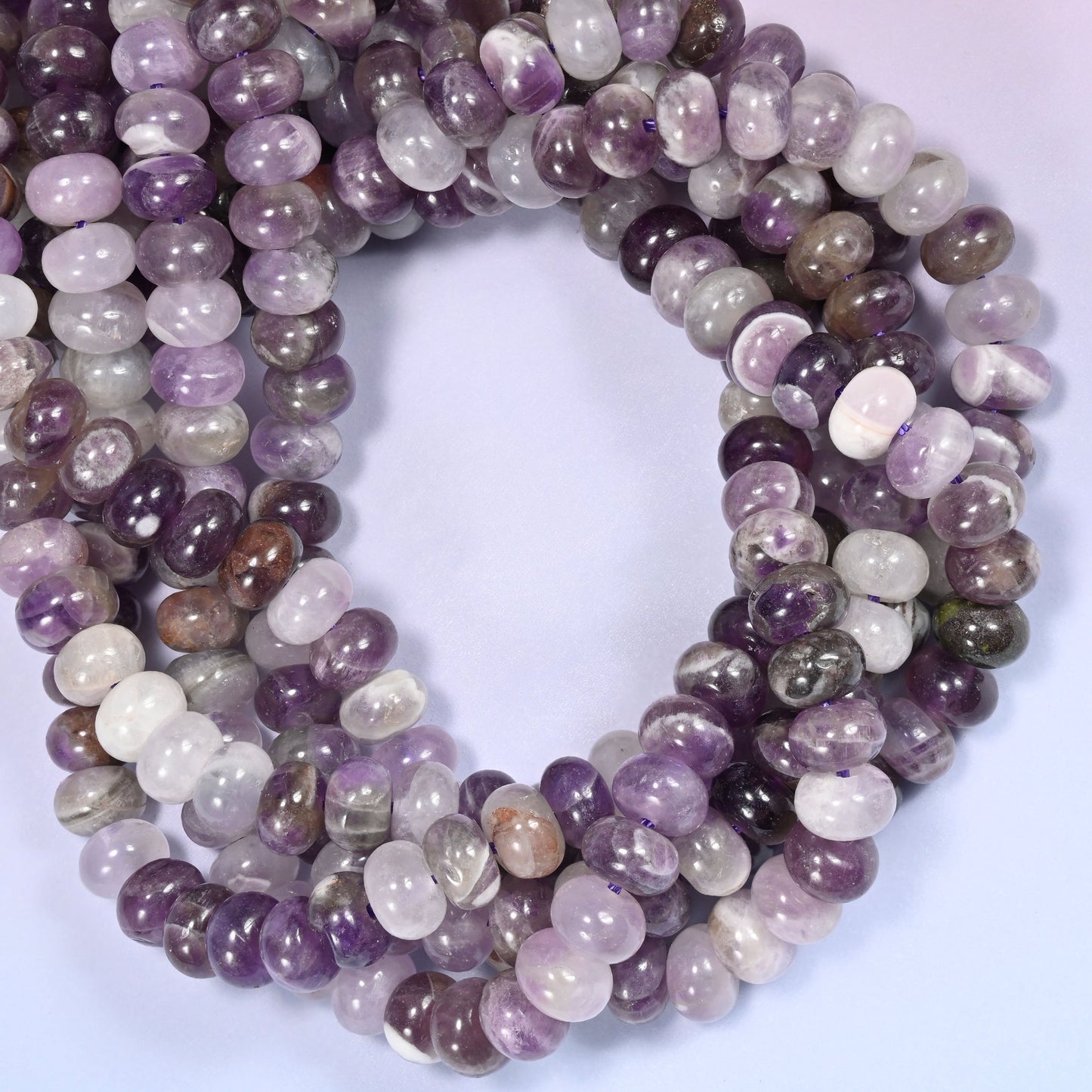Close-up horizontal row of Amethyst beads showing the purple and lavender stone pattern.