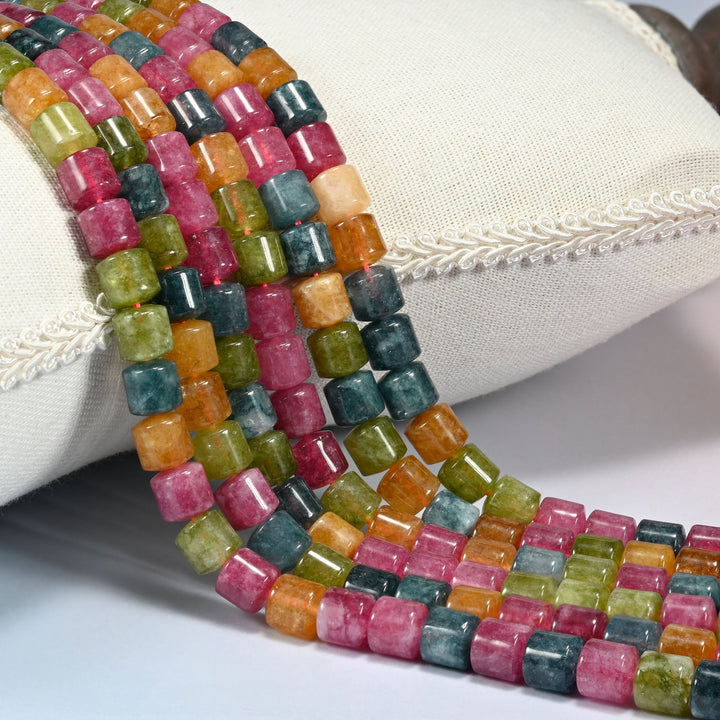 Tourmaline Color Dyed Jade cylinder tube beads 8x8mm draped over a cream cushion, rose pink, olive green, warm orange and teal blue mixed bead to bead along every strand