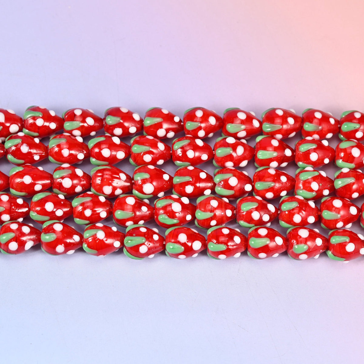 Glossy postbox red strawberry glass beads dotted with white seeds and a green leaf cap
