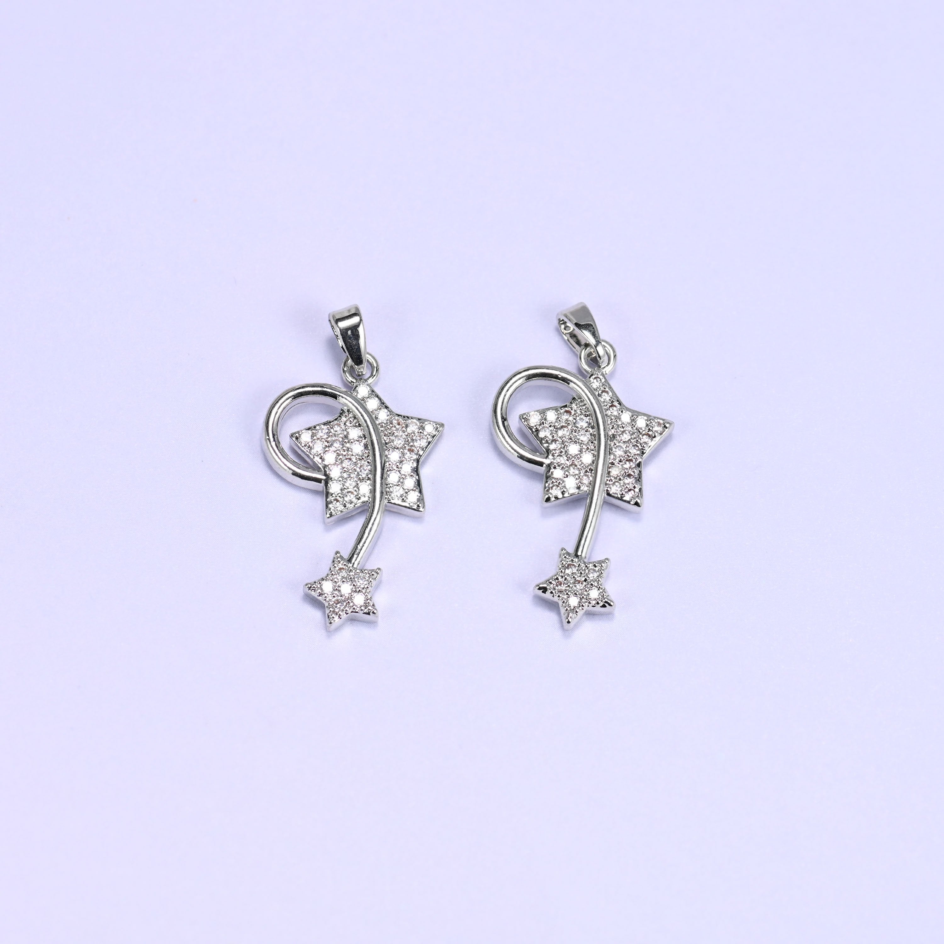 Silver wishing star zirconia charms paired side by side, both shooting star pendants set with clear pave stones.