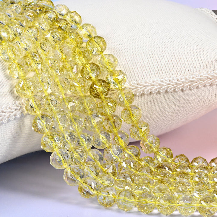 Transparent lemon yellow faceted round glass beads with a clear body that lets the colour pale toward the edges