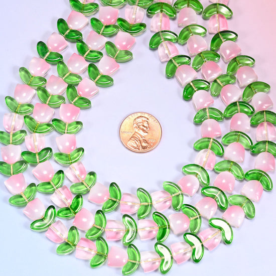 Wide view of a circular coil of pink tulip and green leaf glass bead strands on a lavender background.