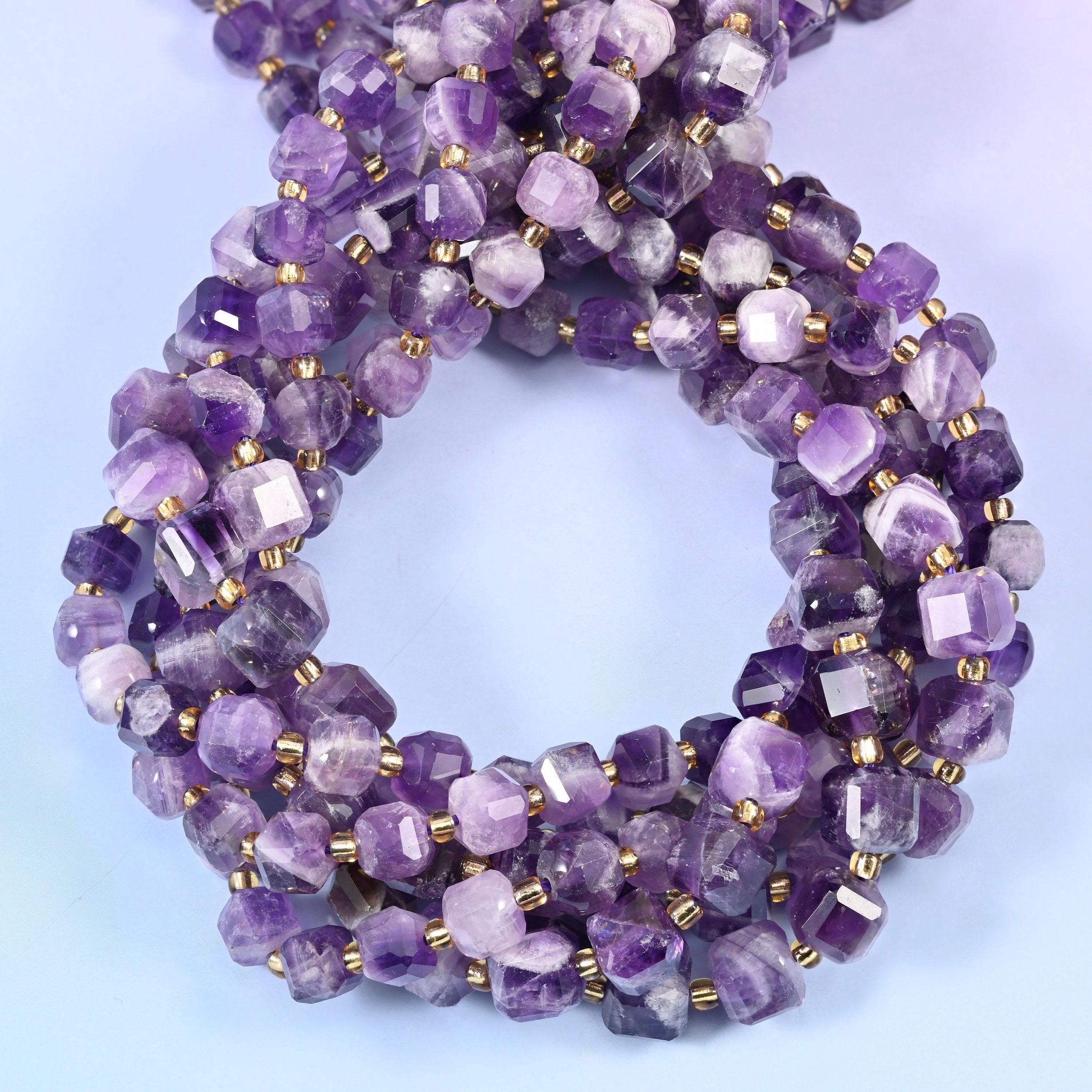 Translucent violet cubes streaked with milky white banding — some beads deep purple, some barely tinted, many split half-and-half straight across