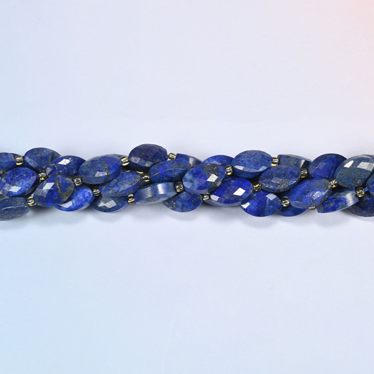 Strands of lapis lazuli faceted flat oval beads twisted together in a horizontal row