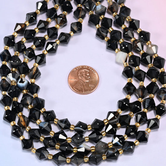 Dyed black strip agate bicone beads coiled into a ring, seen from above, high gloss running across the facets.