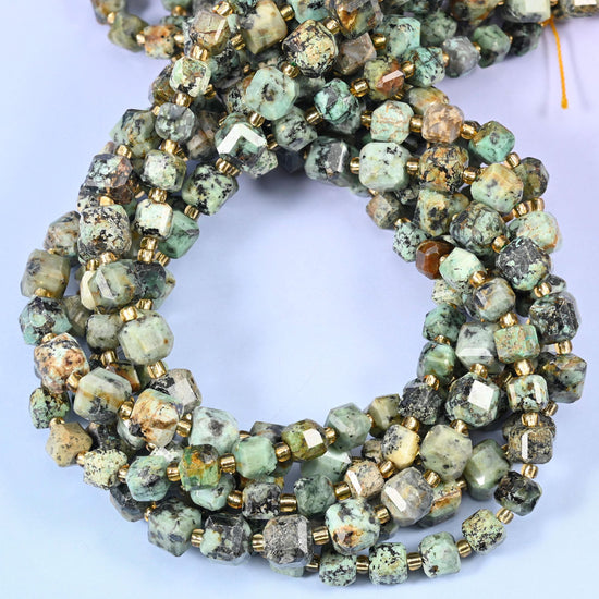 Sage and turquoise green webbed with black matrix veining and the odd bronze-brown patch, squared into cubes with every corner cut back so the veining reads clearly on each flat face.