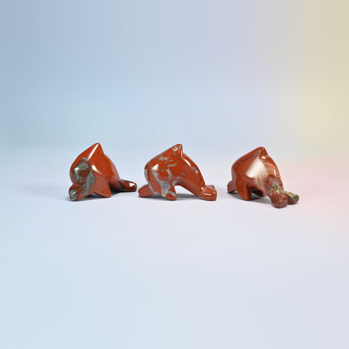 Three red jasper dolphin crystal carvings, brick red natural stone with light veins